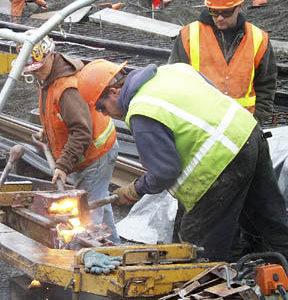 Workers finalize the last weld connecting all the track for Sound Transits 1.6-mile Tacoma Link Light Rail. Service is set to begin in September. (Photo by Brett Davis)