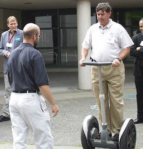 Paul Miller of the Executive Council for a Greater Tacoma tries out Segways Human Transporter during Wednesdays South Sound Technology Conference at the Sheraton. The machine is the worlds first electric, self-balancing transportation device. At left is Paul Worlie, a consultant with Segway. (Photo by Brett Davis)