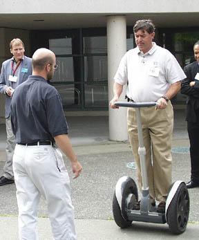 Paul Miller of the Executive Council for a Greater Tacoma tries out Segways Human Transporter during Wednesdays South Sound Technology Conference at the Sheraton. The machine is the worlds first electric, self-balancing transportation device. At left is Paul Worlie, a consultant with Segway. (Photo by Brett Davis)