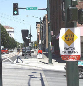 A sign at the corner of Commerce and South 9th streets alerts pedestrians, bicyclists and drivers to watch for passing Link light rail trains, as testing of Tacomas newest transportation system is under way. Its just one part of Sound Transits comprehensive safety campaign. Regular passenger service begins next month. (Photo by Brett Davis)