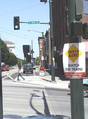 A sign at the corner of Commerce and South 9th streets alerts pedestrians, bicyclists and drivers to watch for passing Link light rail trains, as testing of Tacomas newest transportation system is under way. Its just one part of Sound Transits comprehensive safety campaign. Regular passenger service begins next month. (Photo by Brett Davis)