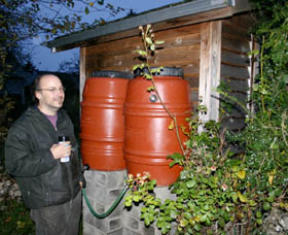 Tacoma resident Dan Borba with his inventions.  Borba manufactures barrels to harvest rainwater. (Photo by Todd Matthews)