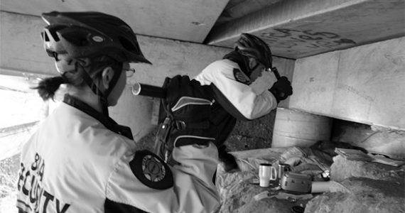 Business Improvement Area bike patrol officers Sarah Kirkman and John Leitheiser inspect a homeless encampment beneath Interstate 705. The officers are a vital security resource downtown. "It's all about respect," says Leitheiser. "If I treat people with respect down here, I'll get that in return." (PHOTO BY TODD MATTHEWS)