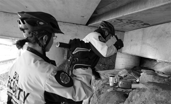 Business Improvement Area bike patrol officers Sarah Kirkman and John Leitheiser inspect a homeless encampment beneath Interstate 705. The officers are a vital security resource downtown. "It's all about respect," says Leitheiser. "If I treat people with respect down here, I'll get that in return." (PHOTO BY TODD MATTHEWS)