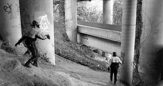 Downtown Tacoma BIA bike patrol officers Sarah Kirkman and John Leitheiser carefully make their way beneath I-705. They regularly inspect the area for homeless encampments. (PHOTO BY TODD MATTHEWS)