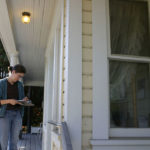 Chase and Johnson leave a business card and letter describing their project for the absent owner of a heritage home. (PHOTO BY TODD MATTHEWS)