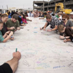 Members of the public sign one of the concrete segments that will form the future walls of the tunnel. (PHOTO COURTESY WSDOT)