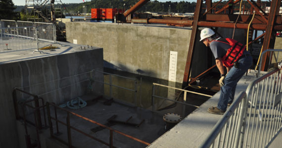 Six more stability pontoons for the State Route 520 bridge floated out of Tacoma July 27. A WSDOT engineer looks on as the T-pontoon squeezes between pontoons in the casting basin. The T-pontoon, specially built for these pontoons, removes the supplemental stability pontoons from the casting basin in pairs. (PHOTO COURTESY WSDOT)