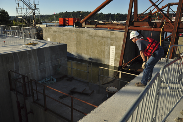 Six more stability pontoons for the State Route 520 bridge floated out of Tacoma July 27. A WSDOT engineer looks on as the T-pontoon squeezes between pontoons in the casting basin. The T-pontoon, specially built for these pontoons, removes the supplemental stability pontoons from the casting basin in pairs. (PHOTO COURTESY WSDOT)