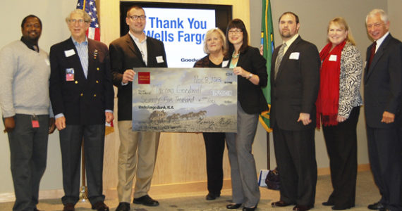 Wells Fargo Tacoma Commercial Banking representative Kari Scott (fourth from right) presented a cardboard check to Tacoma Goodwill Board Chairman Chad Wright (third from left) to symbolize the bank's $75,000 donation to Operation: GoodJobs during a ceremony Friday at Tacoma Goodwill headquarters. Other event participants included (from left to right) Nathen Wright, Operation GoodJobs participant (US Army); Pat Steel, Chairman of the Board for Goodwill Contracting Services (Retired Colonel, US Army); Terry Hayes, Tacoma Goodwill CEO; Mike Tassin, Veterans Services Manager (Operation GoodJobs); Christa Brothers, Tacoma Goodwill Chief Development Officer; and Frank Scoggins, Tacoma Goodwill Board Secretary (General, USAF retired). (PHOTO COURTESY TACOMA GOODWILL)