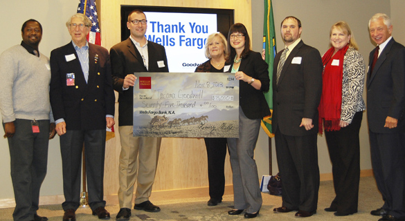 Wells Fargo Tacoma Commercial Banking representative Kari Scott (fourth from right) presented a cardboard check to Tacoma Goodwill Board Chairman Chad Wright (third from left) to symbolize the bank's $75,000 donation to Operation: GoodJobs during a ceremony Friday at Tacoma Goodwill headquarters. Other event participants included (from left to right) Nathen Wright, Operation GoodJobs participant (US Army); Pat Steel, Chairman of the Board for Goodwill Contracting Services (Retired Colonel, US Army); Terry Hayes, Tacoma Goodwill CEO; Mike Tassin, Veterans Services Manager (Operation GoodJobs); Christa Brothers, Tacoma Goodwill Chief Development Officer; and Frank Scoggins, Tacoma Goodwill Board Secretary (General, USAF retired). (PHOTO COURTESY TACOMA GOODWILL)