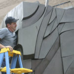 Employees working for D & D Construction prepare to move one section of the three-ton, 15-foot-tall, 22-foot-wide bronze-and-steel Sun King sculpture out of storage at the City of Tacoma's Fleet Operations Headquarters and onto flatbed trailers for transport to a public park near Thea Foss Waterway. (PHOTO BY TODD MATTHEWS)