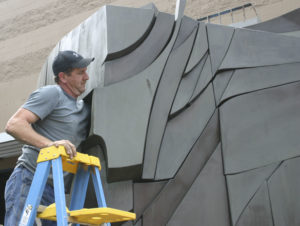 Employees working for D & D Construction prepare to move one section of the three-ton, 15-foot-tall, 22-foot-wide bronze-and-steel Sun King sculpture out of storage at the City of Tacoma's Fleet Operations Headquarters and onto flatbed trailers for transport to a public park near Thea Foss Waterway. (PHOTO BY TODD MATTHEWS)