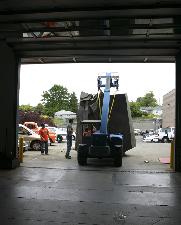 Employees working for D & D Construction prepare to move one section of the three-ton, 15-foot-tall, 22-foot-wide bronze-and-steel Sun King sculpture out of storage at the City of Tacoma's Fleet Operations Headquarters and onto flatbed trailers for transport to a public park near Thea Foss Waterway. (PHOTO BY TODD MATTHEWS)