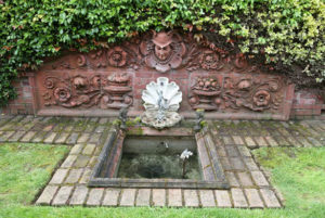 A brick wall bordering a backyard garden at the Mead House includes terra cotta tiles and a figurehead of a helmeted firefighter (known as the 'Head of Mercury') that were salvaged from the former Fire Station No. 6 in downtown Tacoma, which was built in 1890. The fire station was damaged during an earthquake in 1949 and demolished in 1974. (PHOTO COURTESY SUSAN JOHNSON / ARTIFACTS CONSULTING)