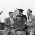 Tacoma Fire Chief Charles Eisenbacher (left) and emergency personnel pose with the 'Head of Mercury' figurehead in 1949. The sculpture was salvaged from the former Fire Station No. 6 in downtown Tacoma, which was built in 1890, damaged during an earthquake in 1949, and demolished in 1974. It is now part of a brick wall that borders a backyard garden at the Mead House. (PHOTO COURTESY SUSAN JOHNSON / ARTIFACTS CONSULTING VIA TACOMA PUBLIC LIBRARY / NORTHWEST ROOM)