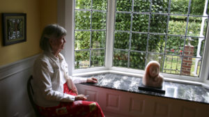 Homeowner Lari Ryan sits near a bay window salvaged from the circa-1889 Hewitt House and repurposed in the dining room of the Mead House. (PHOTO BY TODD MATTHEWS)