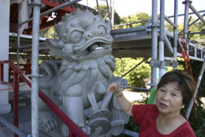 Chinese Reconciliation Project Foundation President Theresa Pan Hosley points out a stone lion statue damaged by vandals. (PHOTO BY TODD MATTHEWS)