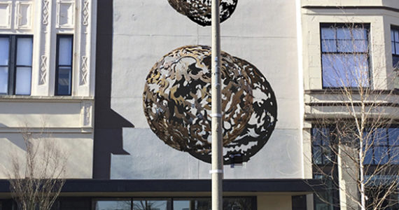 The art installation consists of a trio of three-dimensional metal, laser-cut half-spheres that range in diameter between three feet, five feet, and eight feet, and feature an intricate design pattern. The pieces will be bolted to a blank facade situated between two historic buildings on Broadway. (IMAGE COURTESY JONATHAN CLARREN)