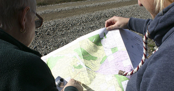 Barbara Reid and Hancock Forest Management Assistant Forester Heather A. Watson consult a map. A section of The Divide is in the distance. (PHOTO BY TODD MATTHEWS)