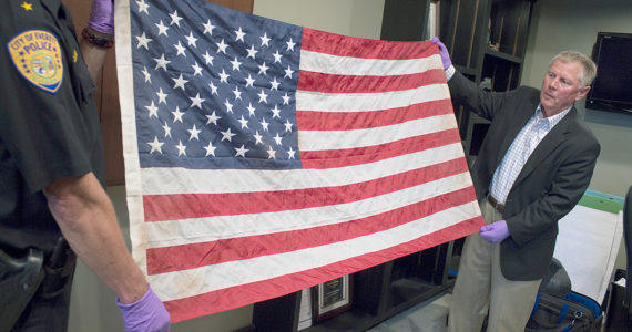 Everett Mayor Ray Stephanson (right) and Deputy Police Chief Mark St. Clair display a flag that is believed to be the one shown in a famous photo of ground zero in New York after the Sept. 11, 2001, terrorist attacks. Credit: City of Everett