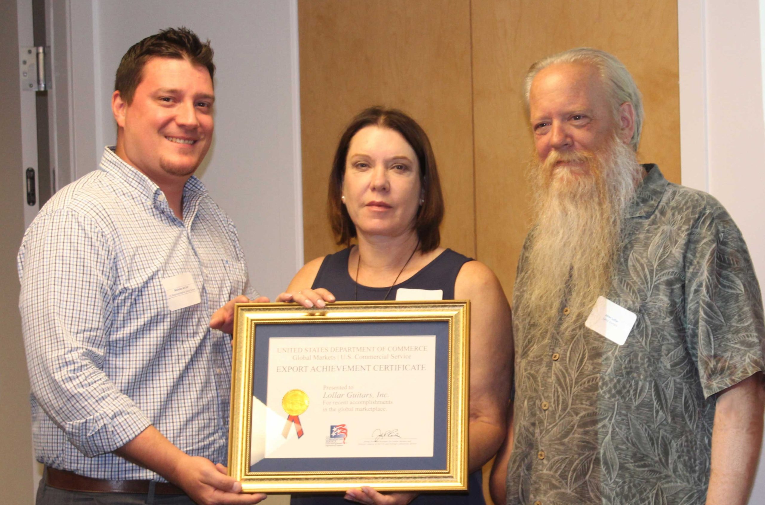 Rep. Kilmer’s District Representative Nicholas Carr (left) presents a U.S. Commercial Service Export Achievement Certificate to Stephanie and Jason Lollar of Lollar Guitars Inc. (right).Image courtesy U.S. Commercial Service