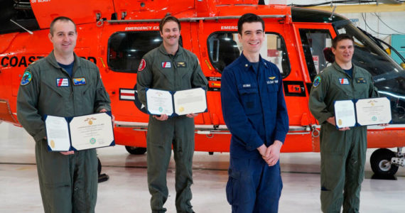 Petty Officer 3rd Class Alexander Neuman, an avionics electrical technician, presents medals to fellow aircrew members Cmdr. Michael Baird, Lt. Cmdr. Joshua Smith, and Petty Officer 2nd Class Chad Morris, at a ceremony held at Coast Guard Sector North Bend, Oregon, April 30, 2020. Baird, Smith, and Morris saved Neuman’s life in October 2019 by giving him CPR. (U.S. Coast Guard photo courtesy of Sector North Bend)