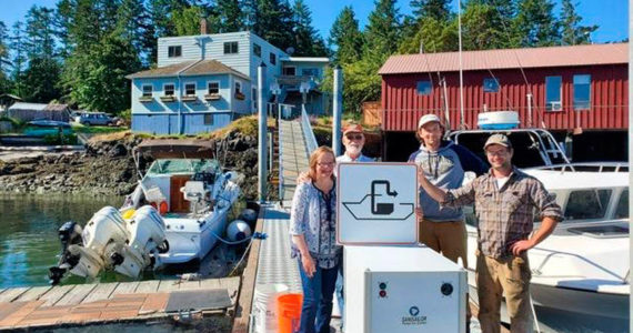 Shaw Island General Store owners Terri and Steve Mason and employees Nick Burne and Jonathan Hogue stand by the pumpout facility that was installed last summer. Image courtesy Washington Sea Grant