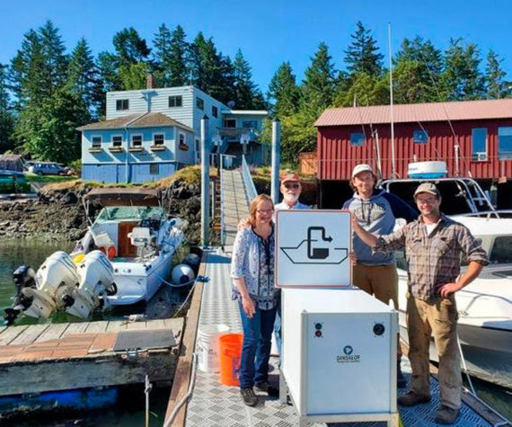 <p>Shaw Island General Store owners Terri and Steve Mason and employees Nick Burne and Jonathan Hogue stand by the pumpout facility that was installed last summer. Image courtesy Washington Sea Grant</p>