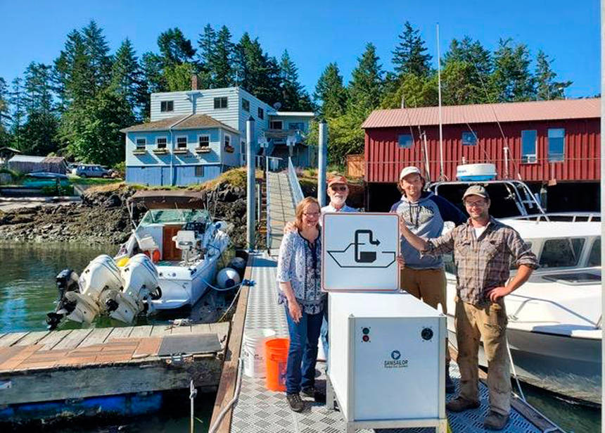 Shaw Island General Store owners Terri and Steve Mason and employees Nick Burne and Jonathan Hogue stand by the pumpout facility that was installed last summer. Image courtesy Washington Sea Grant