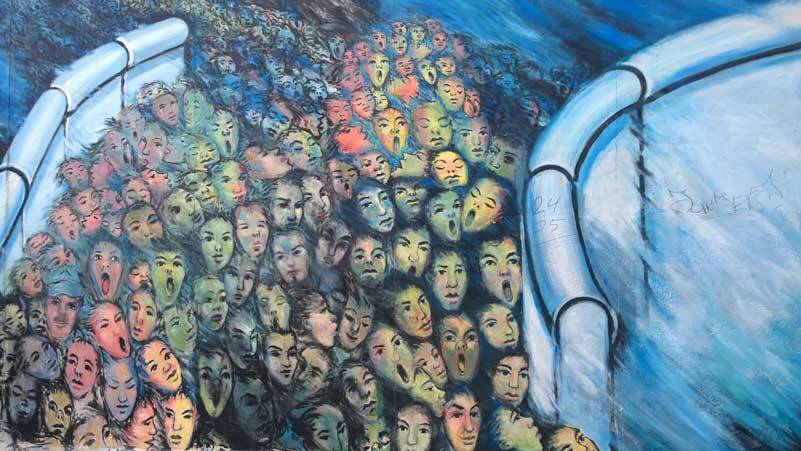 “Huddled masses yearning to breathe free” - this detail from the Berlin Wall captures the essence of humans bound by a confining infrastructure pushing their way to a more life-affirming one. (Photo by Morf Morford)