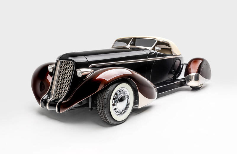 <p>“SLOW BURN”</p>
                                <p>SPECS: 1936 AUBURN 852 BOATTAIL SPEEDSTER (MODERN REPLICA) BUILDER: RICK DORE KUSTOMS INTERIOR: EGYPTIAN LEATHER BY BOB DEVINE/RICK DORE ENGINE: 350-CUBIC INCH CHEVROLET V-8</p>
                                <p><em>Image courtesy LeMay-America’s Car Museum, Petersen Automotive Museum and the Hetfield Family</em></p>
                                <p>Bio: “Slow Burn” was crafted from an official Glen Pray recreation of an Auburn Boattail. The fiberglass body made it difficult to alter extensively, so Hetfield and Dore instead added details, like a sloped, Carson-style convertible top, to emphasize the car’s curving lines. The root beer paint color of the fenders, in contrast with the darker body color, highlights their sinuous shape. Accents like the geometric grille, taillight trim, and personally designed wheels exemplify Hetfield’s personal style.</p>
