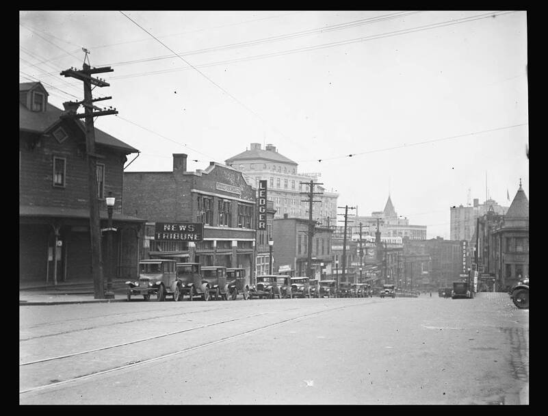 This photograph from May of 1928 shows the buildings on the east side of St. Helens Avenue from 7th Street looking south. Second in from the corner is the building that was shared by the News Tribune and the Tacoma Daily Ledger from 1918 to 1937. Built in 1910 by Darmer & Cutting for the News Tribune, the Ledger moved into the building when it was bought out by the Tribune in 1918. Both papers published independently from this building until the Daily Ledger went out of business in 1937. The News Tribune kept the name of the Ledger alive in the masthead of its Sunday paper until August of 1979, The Tacoma News Tribune and Sunday Ledger. Image and text courtesy Tacoma Public Library, (Chapin Bowen Collection BGN-720)