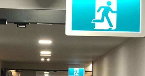 These emergency exit signs sum up our economy. Which way to run depends on where you are when. (Photo by Morf Morford)