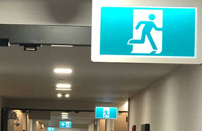 These emergency exit signs sum up our economy. Which way to run depends on where you are when. (Photo by Morf Morford)