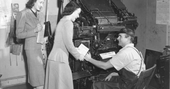 <strong>A Linotype machine is in the background of this image from a 1944 Community War Chest campaign. View of two unidentified War Chest volunteers soliciting funds from an unidentified typesetter. Image courtesy Northwest Room at The Tacoma Public Library, image number: Richards Studio D18294-11</strong>