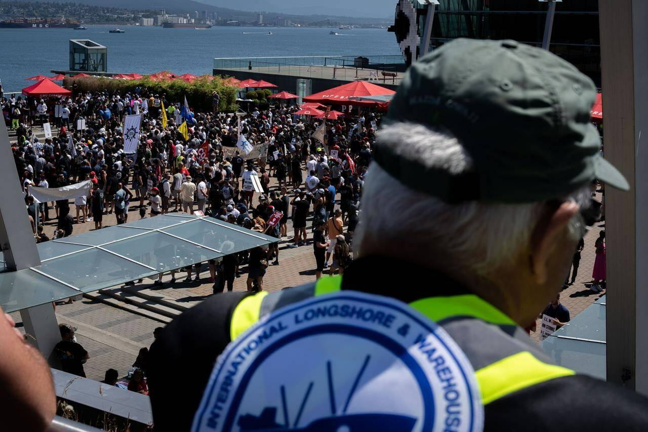 A striking port worker from the International Longshore and Warehouse Union Canada views the large gathering attending a rally in Vancouver, on Sunday, July 9, 2023. THE CANADIAN PRESS/Ethan Cairns