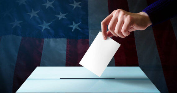 Election in America Concept. Hand Dropping a Ballot Card into the Vote Box, Flag of United States as background
