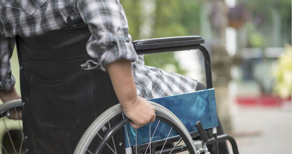 Close-up of senior woman hand on wheel of wheelchair during walk in hospital. File photo