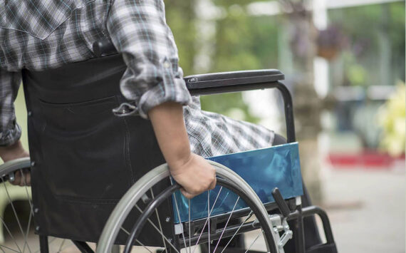 Close-up of senior woman hand on wheel of wheelchair during walk in hospital. File photo