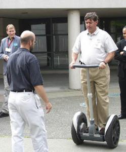 Paul Miller of the Executive Council for a Greater Tacoma tries out Segways Human Transporter during Wednesdays South Sound Technology Conference at the Sheraton. The machine is the worlds first electric, self-balancing transportation device. At left is Paul Worlie, a consultant with Segway. (Photo by Brett Davis)