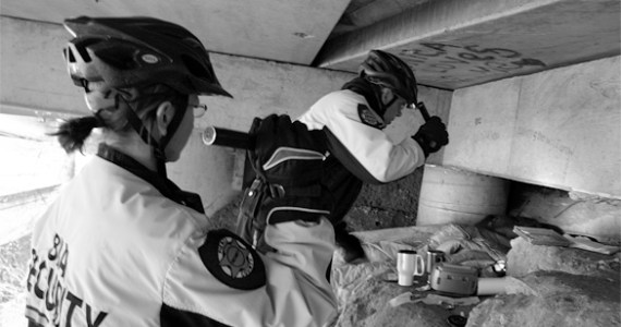 Business Improvement Area bike patrol officers Sarah Kirkman and John Leitheiser inspect a homeless encampment beneath Interstate 705. The officers are a vital security resource downtown. "It's all about respect," says Leitheiser. "If I treat people with respect down here, I'll get that in return." (PHOTO BY TODD MATTHEWS)