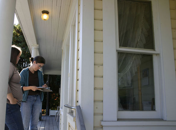Chase and Johnson leave a business card and letter describing their project for the absent owner of a heritage home. (PHOTO BY TODD MATTHEWS)