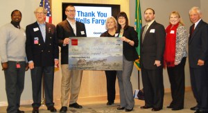 Wells Fargo Tacoma Commercial Banking representative Kari Scott (fourth from right) presented a cardboard check to Tacoma Goodwill Board Chairman Chad Wright (third from left) to symbolize the bank's $75,000 donation to Operation: GoodJobs during a ceremony Friday at Tacoma Goodwill headquarters. Other event participants included (from left to right) Nathen Wright, Operation GoodJobs participant (US Army); Pat Steel, Chairman of the Board for Goodwill Contracting Services (Retired Colonel, US Army); Terry Hayes, Tacoma Goodwill CEO; Mike Tassin, Veterans Services Manager (Operation GoodJobs); Christa Brothers, Tacoma Goodwill Chief Development Officer; and Frank Scoggins, Tacoma Goodwill Board Secretary (General, USAF retired). (PHOTO COURTESY TACOMA GOODWILL)