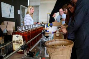 Tacoma Art Museum staff working alongside Heritage Distilling Co.'s crew in Gig Harbor to bottle the final cases of the signature Tacoma New West Bourbon Whiskey, a joint-creation between Heritage Distilling Co. and the Tacoma Art Museum in honor of the November 15 grand opening of the Tacoma Art Museum's Haub Family Collection of Western American Art and museum expansion. (PHOTO BY MYLES LASCO / COURTESY TACOMA ART MUSEUM)
