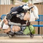 Homeless persons belongings in a shopping cart in a sidewalk