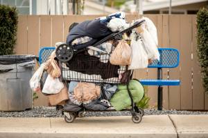 Homeless persons belongings in a shopping cart in a sidewalk