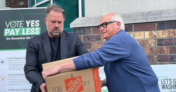Brian Heywood, left, of Lets Go Washington hands a box of signed Initiative 2066 petitions to Greg Lane, executive vice president of the Building Industry Association of Washington on July 2, 2024. (Jerry Cornfield/Washington State Standard)