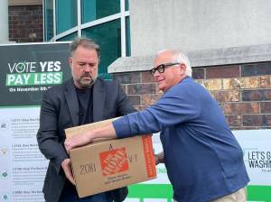 Brian Heywood, left, of Lets Go Washington hands a box of signed Initiative 2066 petitions to Greg Lane, executive vice president of the Building Industry Association of Washington on July 2, 2024. (Jerry Cornfield/Washington State Standard)