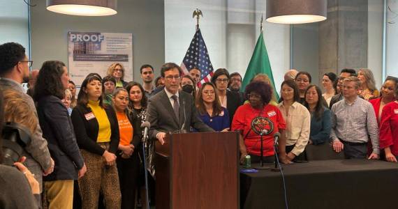 Photo by Jake Goldstein-Street/Washington State Standard 
Gov. Bob Ferguson, podium, makes remarks during a bill signing event on May 7, 2025, where he signed a law that will cap rent increases for many residential tenants across Washington at 10% or less annually.